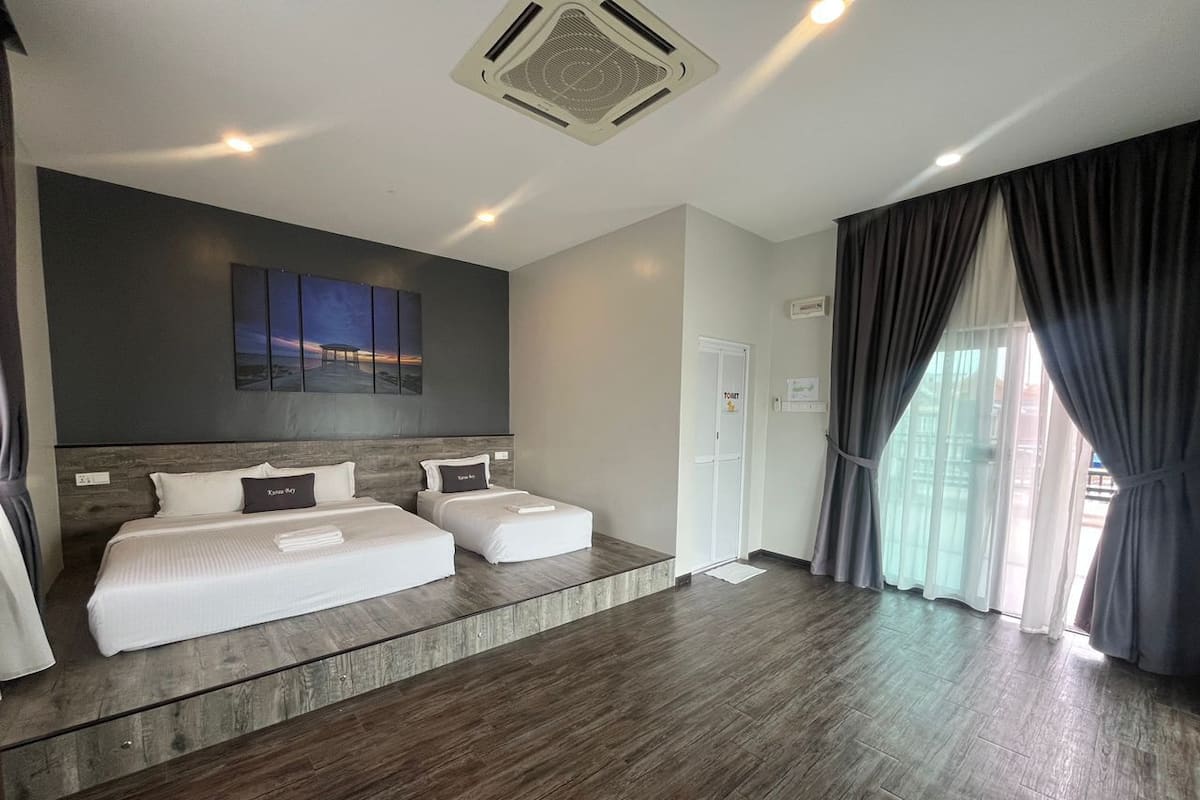 Quarto de hotel moderno com uma cama grande, um espaço de estar, um quadro na parede e vista pela janela.