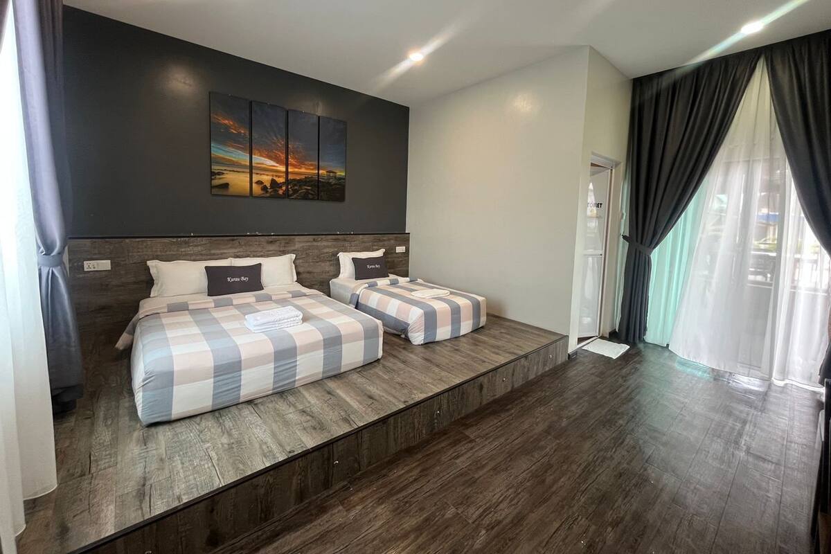 Quarto de hotel moderno com uma cama grande, uma cama menor e uma área de estar.