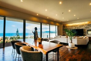 Una sala de estar moderna con una gran mesa de madera, asientos cómodos, un televisor de pantalla plana y una pared de piedra.