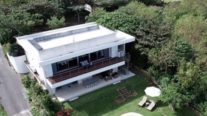 A modern two-story house with a large balcony, a swimming pool, and lush greenery surrounding the property. - A special retreat in Ishigaki Island｜Private villa exclusively for one group per day (ishigaki city)