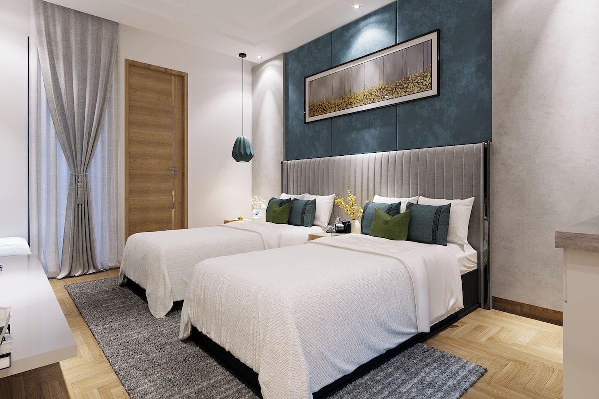 Una camera da letto moderna con due letti, un'ampia finestra con tende, un quadro appeso al muro e un piccolo tavolino con un vaso.