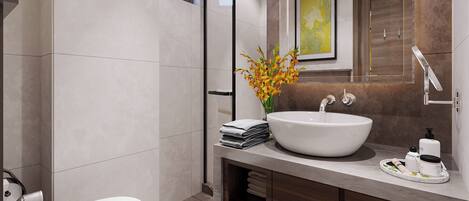 A modern bathroom with a large white sink, a toilet, and a bathtub. There is a wooden vanity with a mirror above the sink, and a framed picture on the wall.