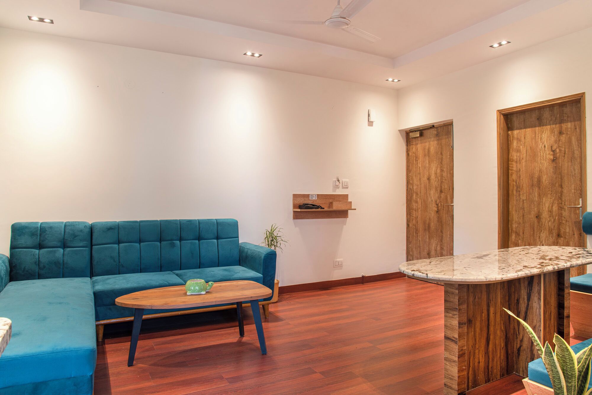 Ein modernes Wohnzimmer mit einem blauen Sofa, einem Holztisch und einer Wand mit Marmorverkleidung.