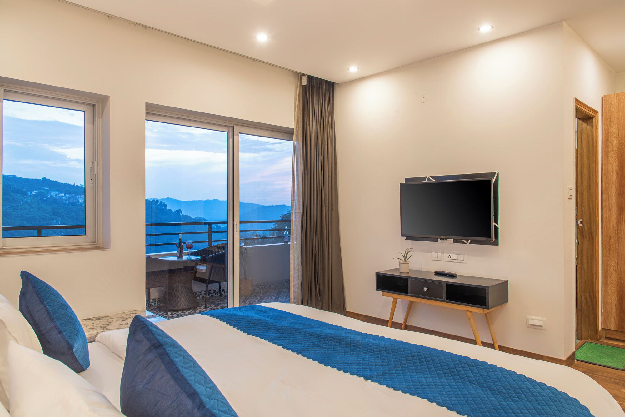 Une chambre avec un lit, une télévision et un balcon offrant une vue.