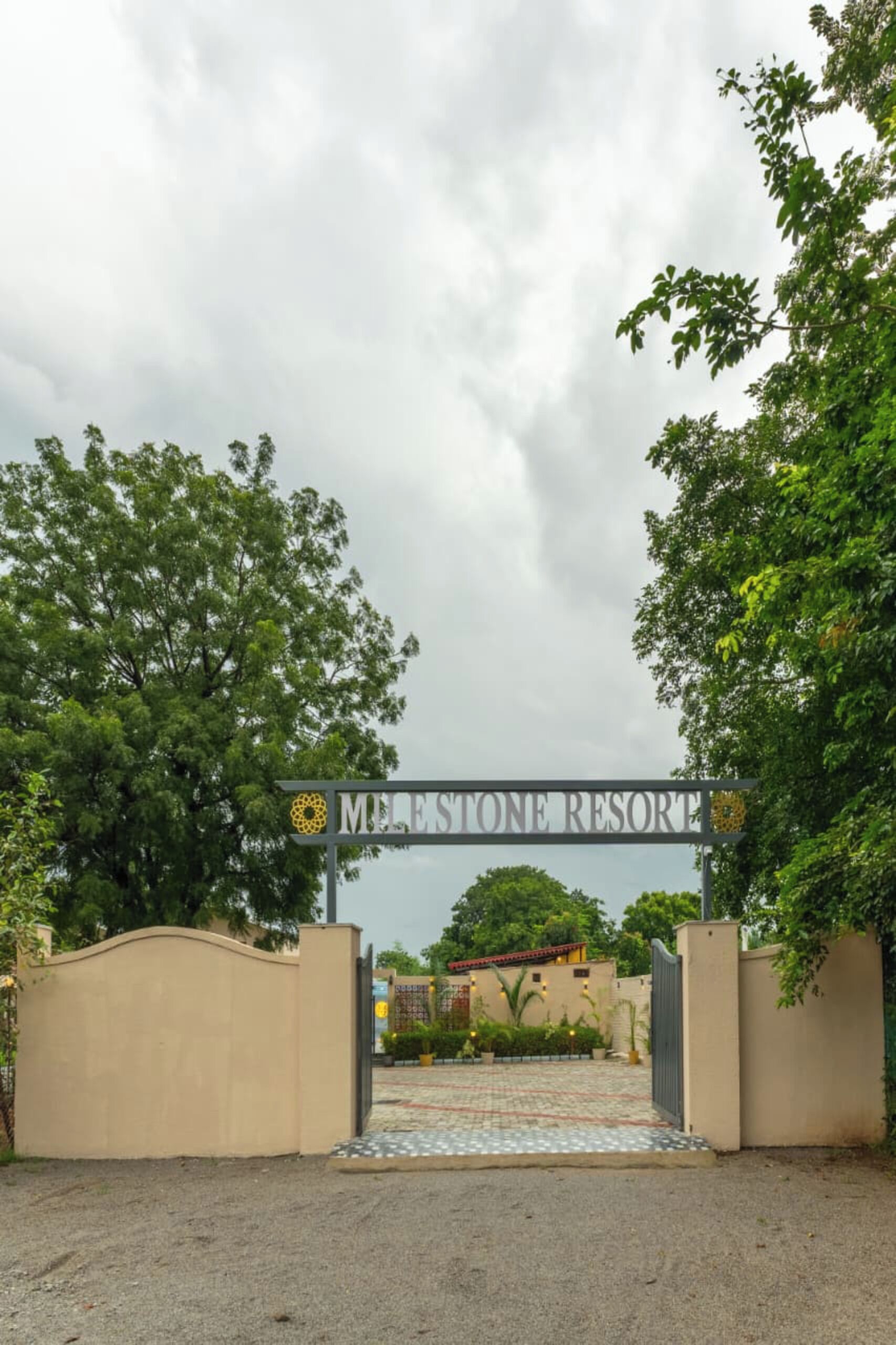 La entrada al Milestone Resort, con un cartel sobre el portón y un camino pavimentado que conduce al edificio.