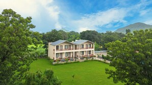 A two-story building with a flat roof, surrounded by lush greenery and a well-maintained lawn. - Milestone Resort (Udaipur)