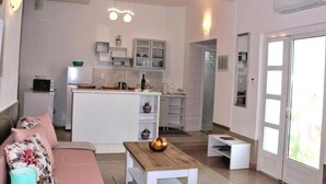 Un salon moderne comprenant un canapé, une table basse et un coin cuisine avec des placards et un four à micro-ondes.