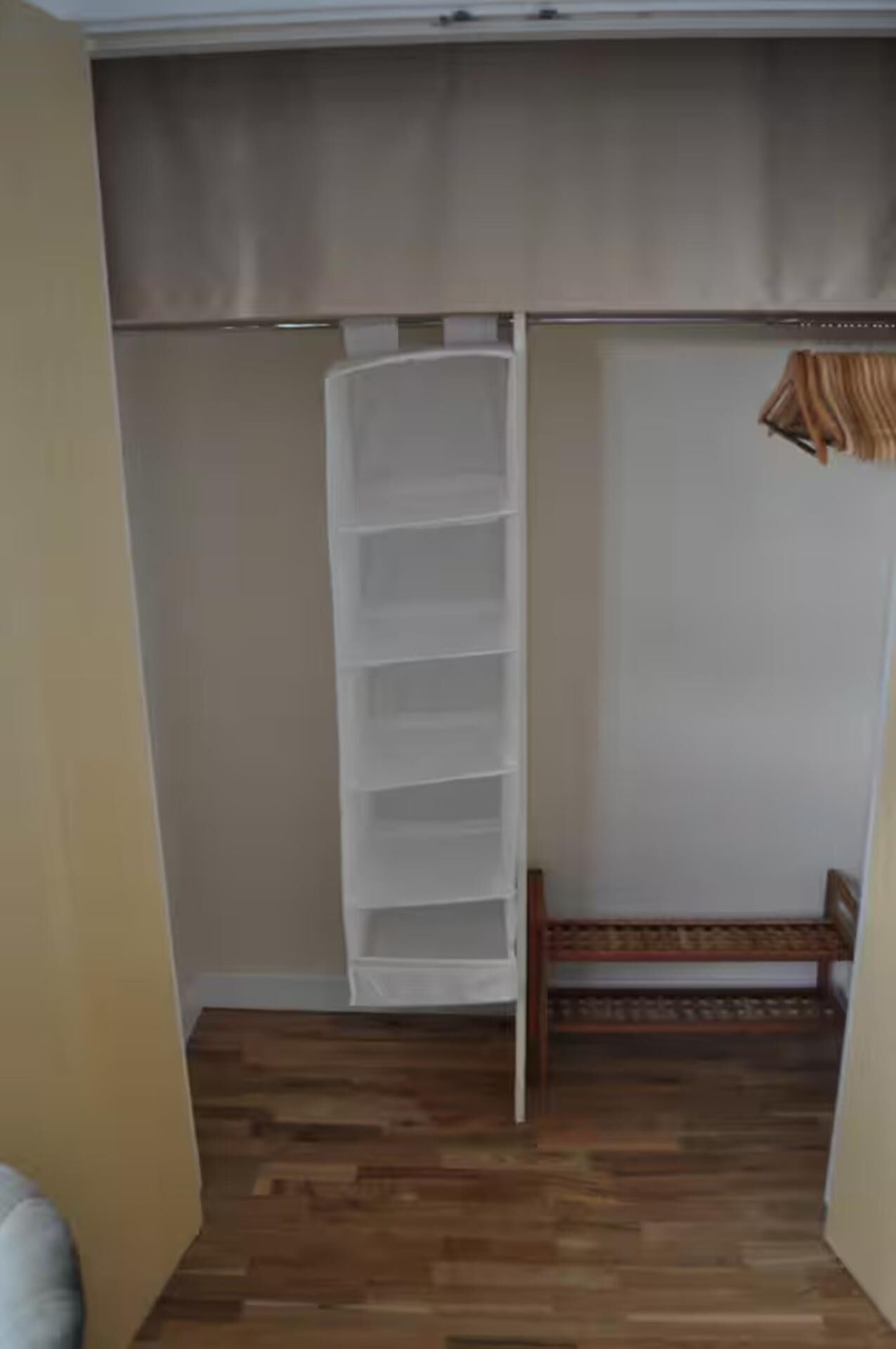 A walk-in closet with a wooden bench and a white shelving unit.