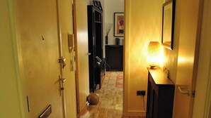A hallway with wooden flooring, a door on the left, and a lamp on the right. - 2-bed Seaside Apartment - Sleeps 5 & Free Parking (Edinburgh)