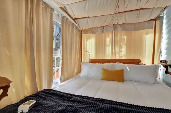A hotel room with a bed, curtains, a bedside table, and a clock.