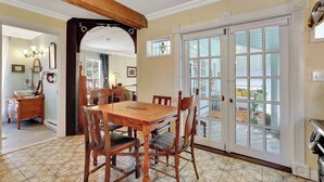 A dining area with a wooden table and chairs, a large window with a view, and a door leading to an outdoor area.