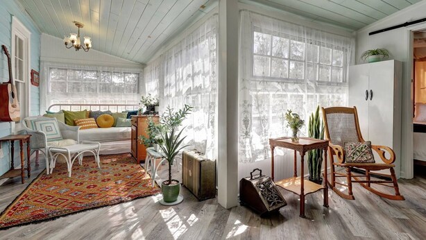 A cozy room with a bed, a rocking chair, a small table, and a colorful rug.