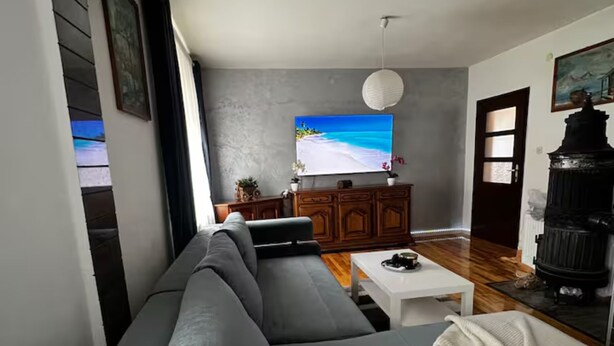 Un salon moderne avec un canapé gris, une table basse blanche et une cheminée noire.