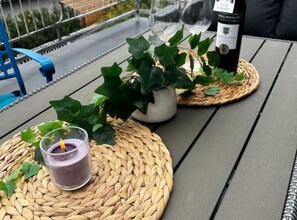 A table with a bottle of wine, a glass of drink, and a potted plant on a woven placemat. - House Burić (Senj)