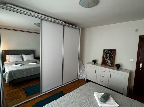 A bedroom with a bed, a wardrobe, a bedside table, and a mirror.