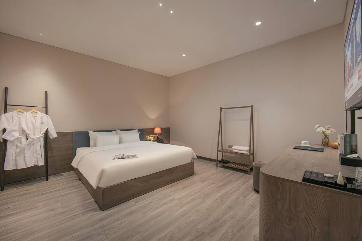 Una habitación de hotel moderna con una cama grande, una mesita de noche y un área de escritorio.