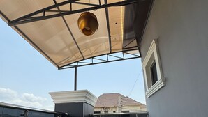 Eine Dachterrasse mit Glasgeländer, einem Tisch und Stühlen sowie einem kleinen Fenster.