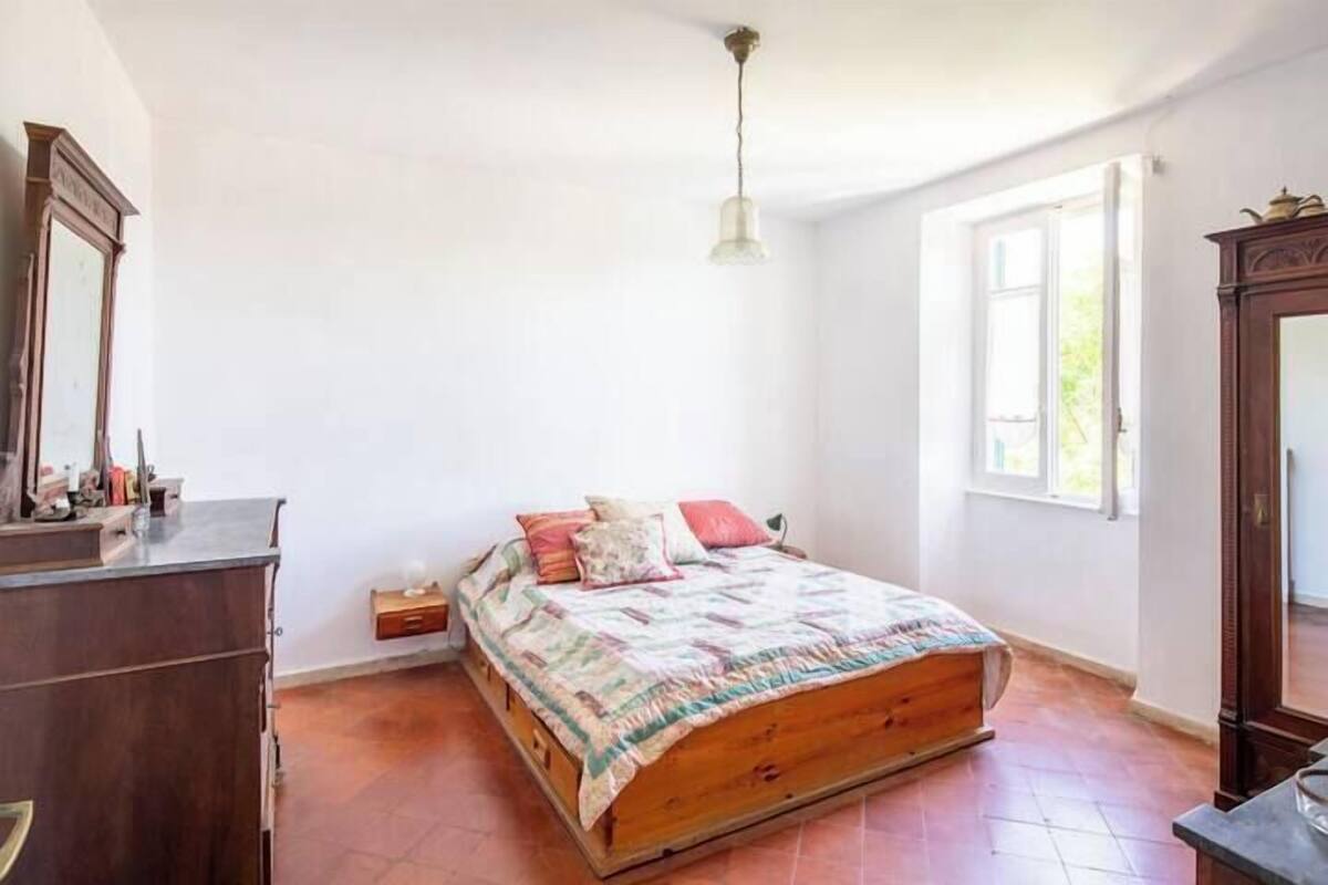 A bedroom with a wooden bed, a dresser, a mirror, and a window with curtains.