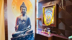 Ein Zimmer mit Buddha-Statue, einem gerahmten Heiligenbild und einem Gebetsaltar.