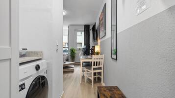 A laundry room with a washing machine, a drying rack, and a wooden bench.