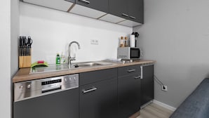 A compact kitchen with a dishwasher, sink, and microwave.