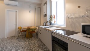 A compact kitchen with a dining area, a built-in microwave, and a window providing natural light. - Cosy two-room apartment Porta Romana - Mirable PM (Milan)