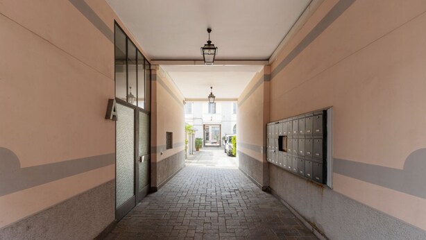 A corridor with lockers, a door, and a view of a building in the distance. - Cosy two-room apartment Porta Romana - Mirable PM (Milan)