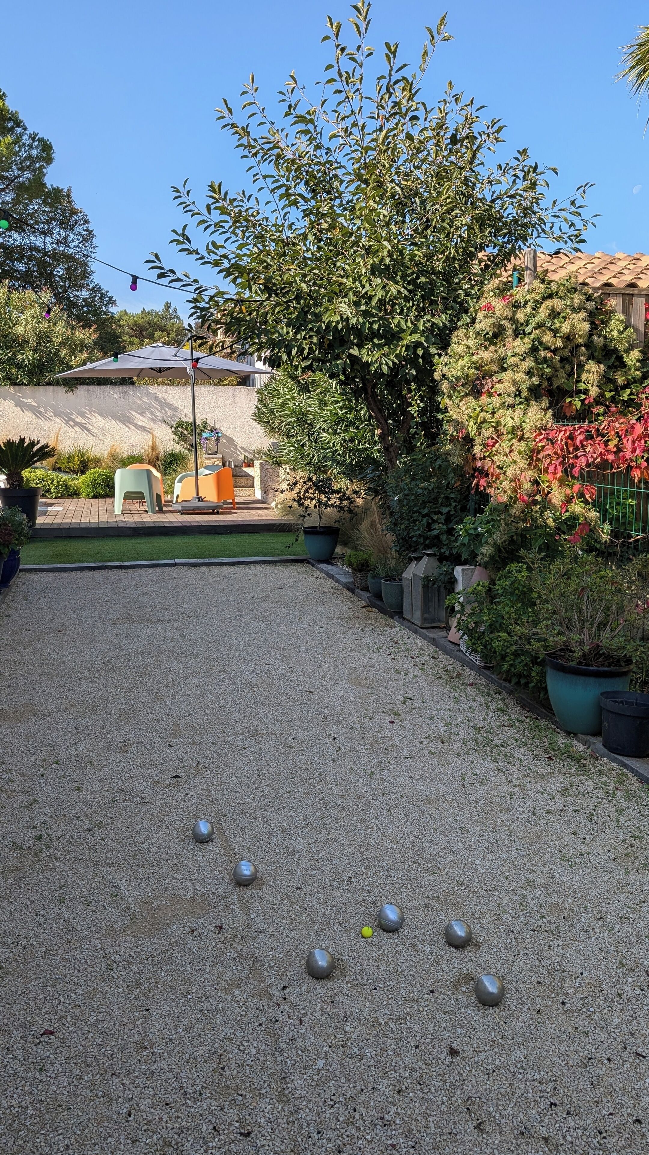 Un patio de grava con un pérgola, zona de estar y diversas plantas.