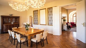 Un coin repas avec une table et des chaises en bois, un lustre et un panneau décoratif mural.