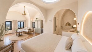 Um quarto espaçoso com uma cama grande, um espaço de estar com uma mesa e vista para o mar através de um claraboia.