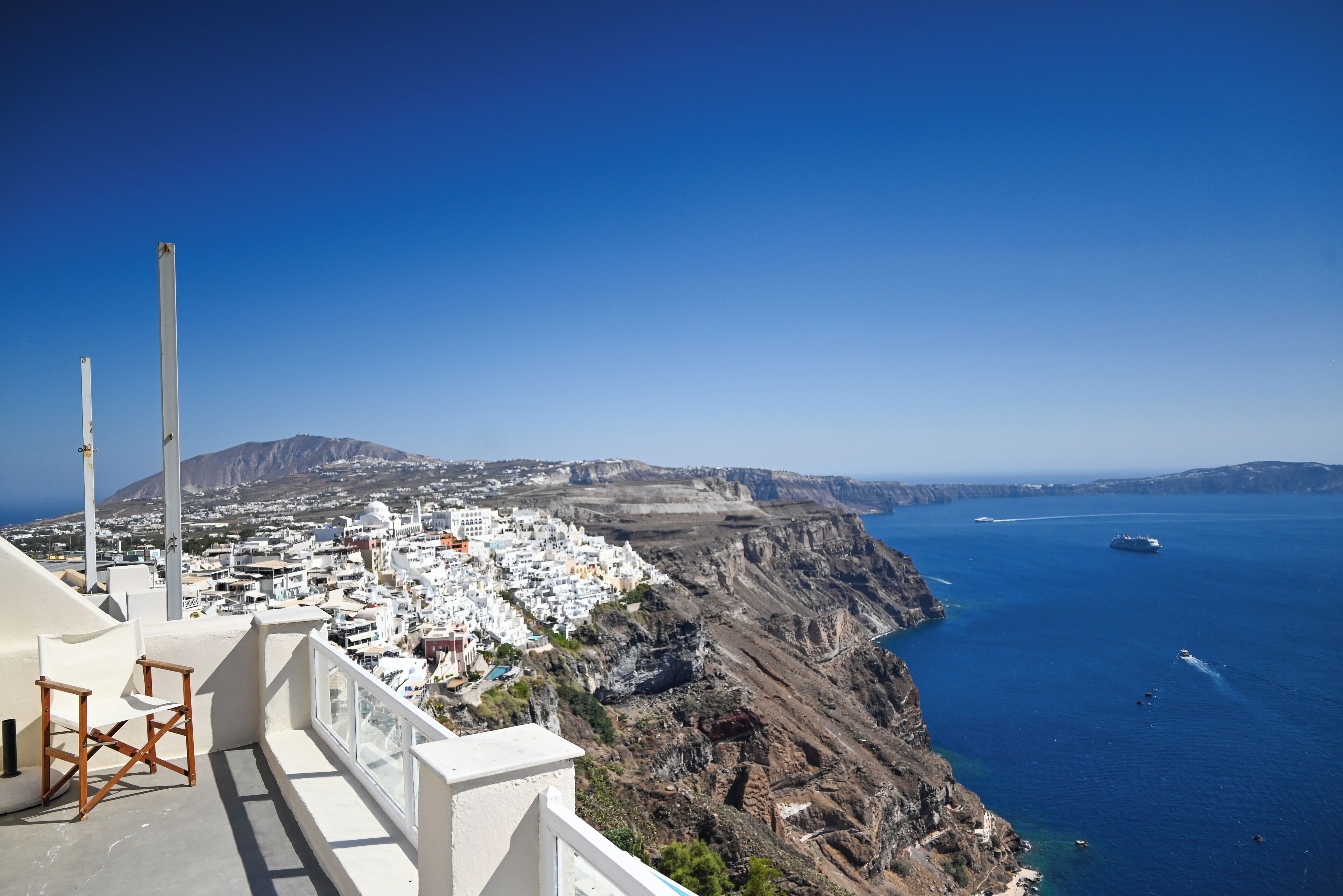 A coastal town with white buildings, a cliffside, and a view of the sea.