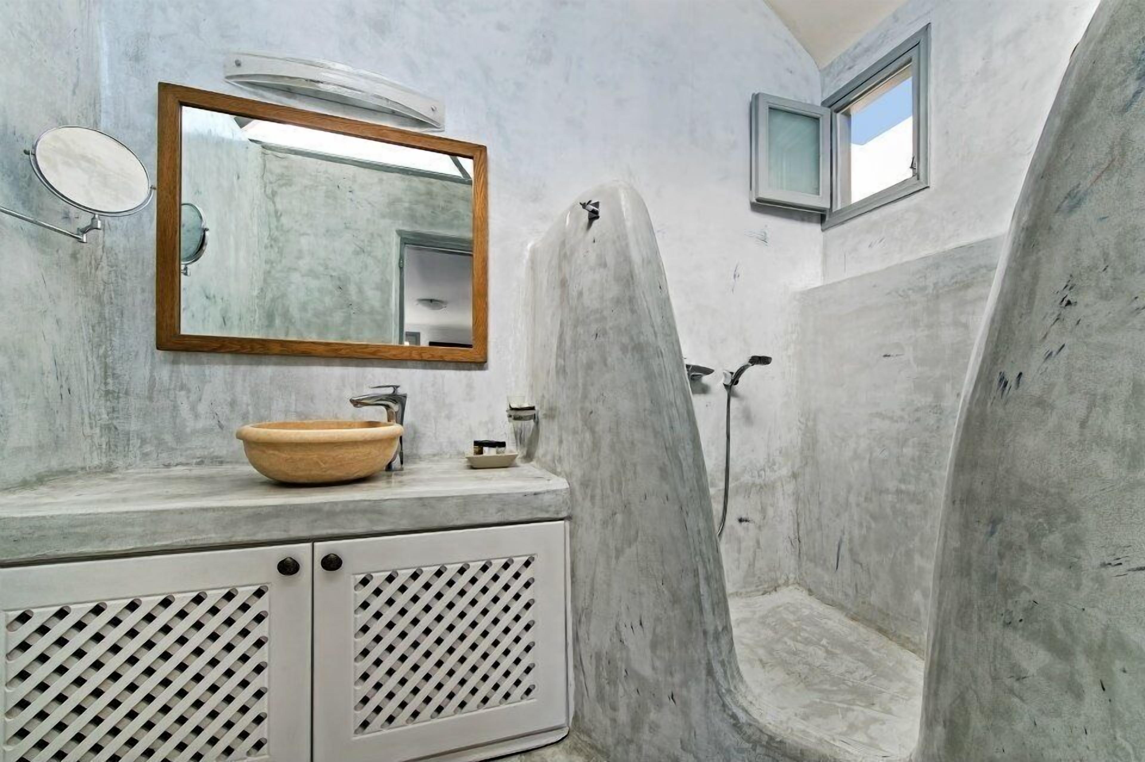 A bathroom with a large mirror, a wooden-framed mirror, a sink with a bowl, and a shower area.
