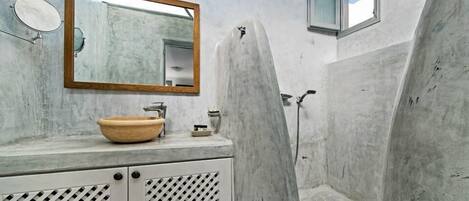 A bathroom with a large mirror, a wooden-framed mirror, a sink with a bowl, and a shower area.