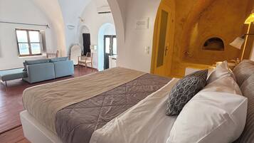 Een ruime slaapkamer met een groot bed, een houten deur en uitzicht op de aangrenzende woonruimte.