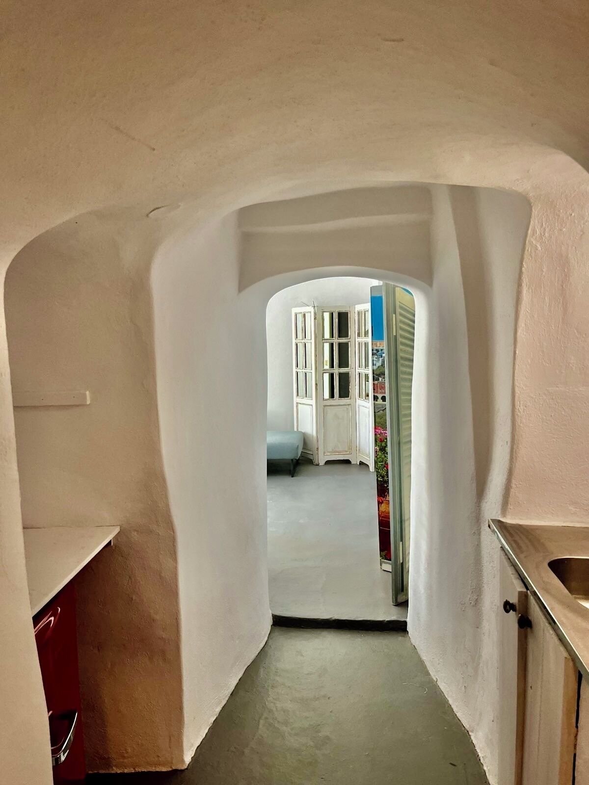 Un pasillo estrecho que conduce a una habitación con cama y ventana.