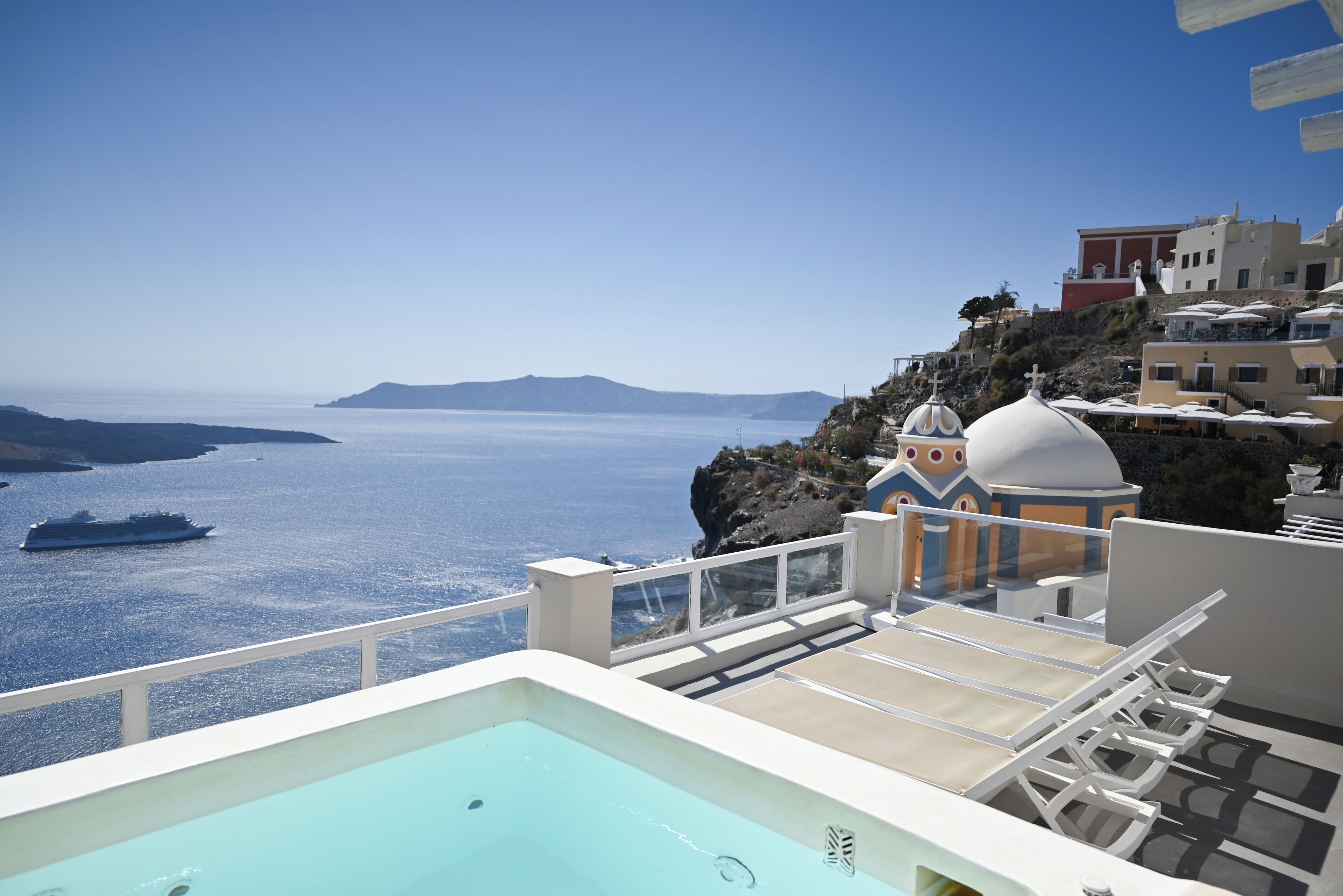 A pool area with a view of the sea and a building with a dome-shaped roof.