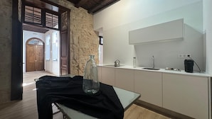 A modern kitchen with a stone wall, wooden beams, a glass table, and a black cloth. - Doña Perfecta -El 11 De López Botas-. (Las Palmas)