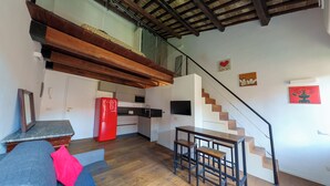 Um espaço de estar compacto com cozinha, sala de jantar e escada.