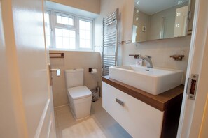 Un baño moderno con inodoro, lavabo y espejo.