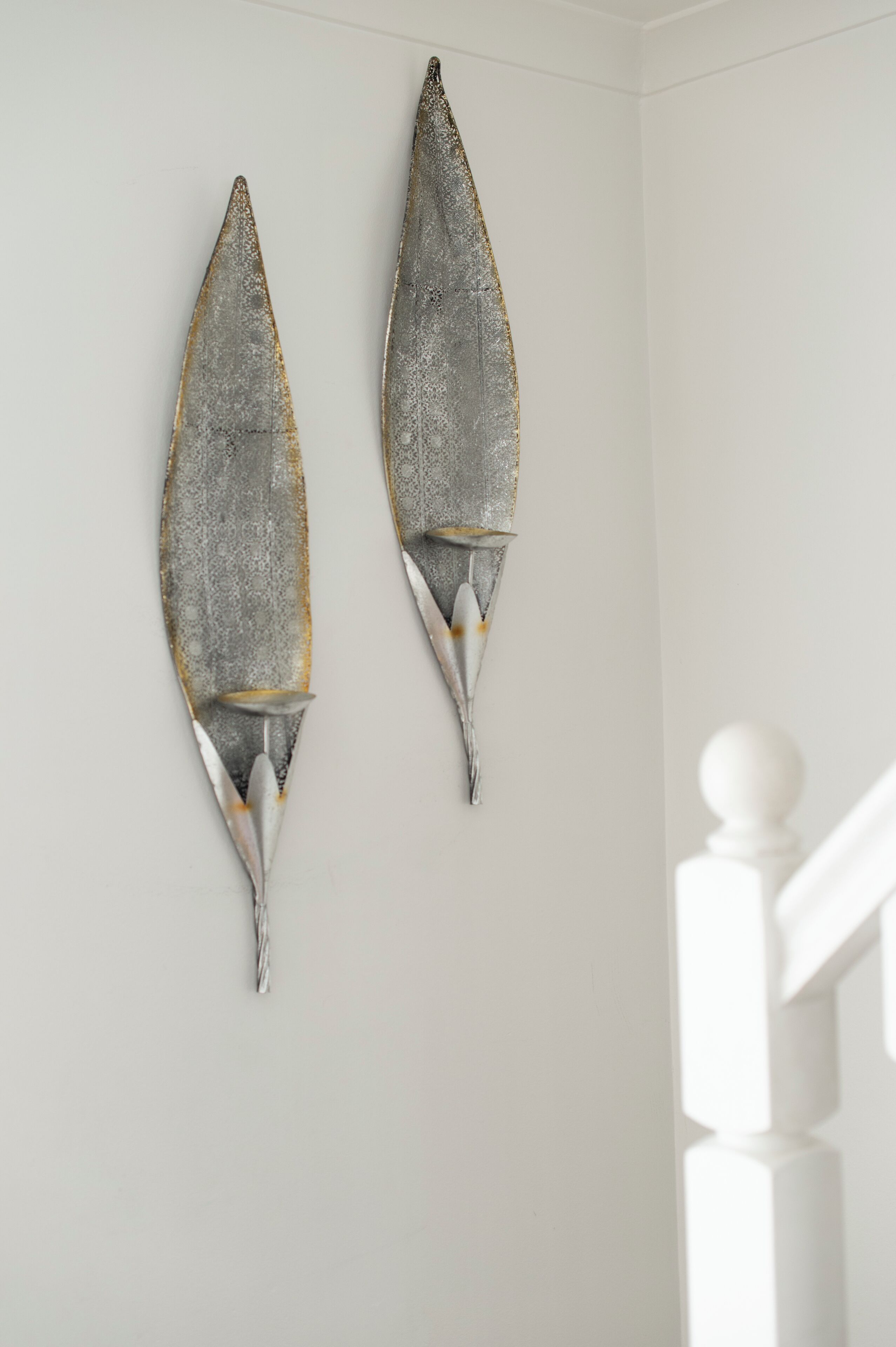 Two wall-mounted decorative fish sculptures in a room with white walls and a white staircase.
