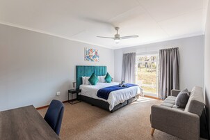Un dormitorio moderno con una cama, un escritorio, una silla y un sofá.