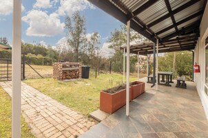Un patio techado con una parrilla de ladrillo, asientos exteriores y un extintor.