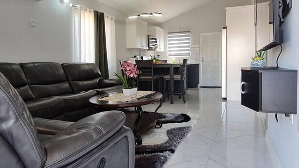 Una sala moderna con un sofá de cuero, una mesa de centro y un comedor con una mesa y sillas.