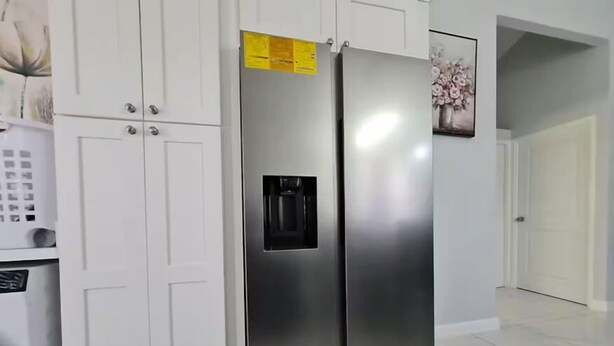 A stainless steel refrigerator with a water dispenser, white cabinetry, and a tiled floor. - Cozy Relaxing Home in Old Harbour (Old Harbour)