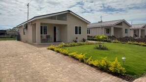 Un edificio residencial moderno con entrada pavimentada y césped bien cuidado.