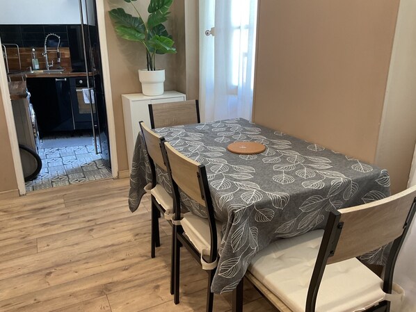 A dining area with a table covered by a leaf-patterned tablecloth, surrounded by chairs with cushioned seats. - Le P'tit St Charles Arrive, pack your bags, breathe: you're in Marseille. (Marseille)