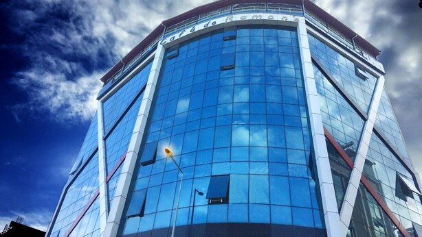 Um edifício moderno com fachada de vidro curva e uma placa com a inscrição