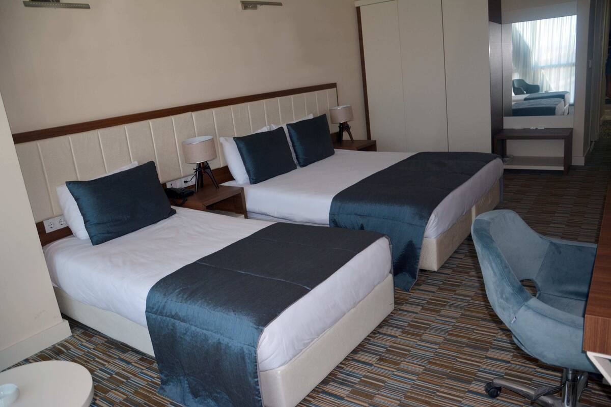 Ein Hotelzimmer mit zwei Betten, einem Schreibtisch, einem Stuhl und einem Badezimmer.