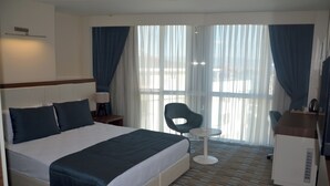 Quarto de hotel com uma cama grande, uma mesa, uma cadeira e uma pequena mesa.