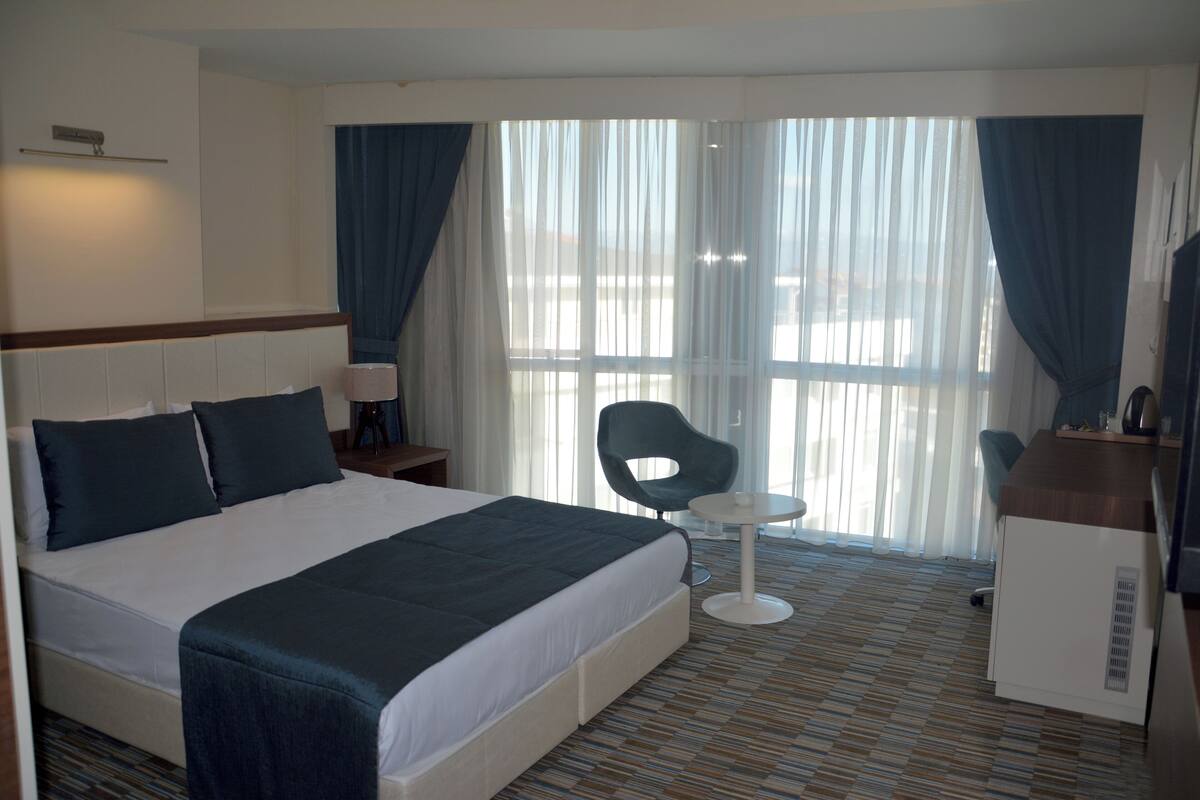 Ein Hotelzimmer mit einem großen Bett, einem Schreibtisch, einem Stuhl und einem kleinen Tisch.